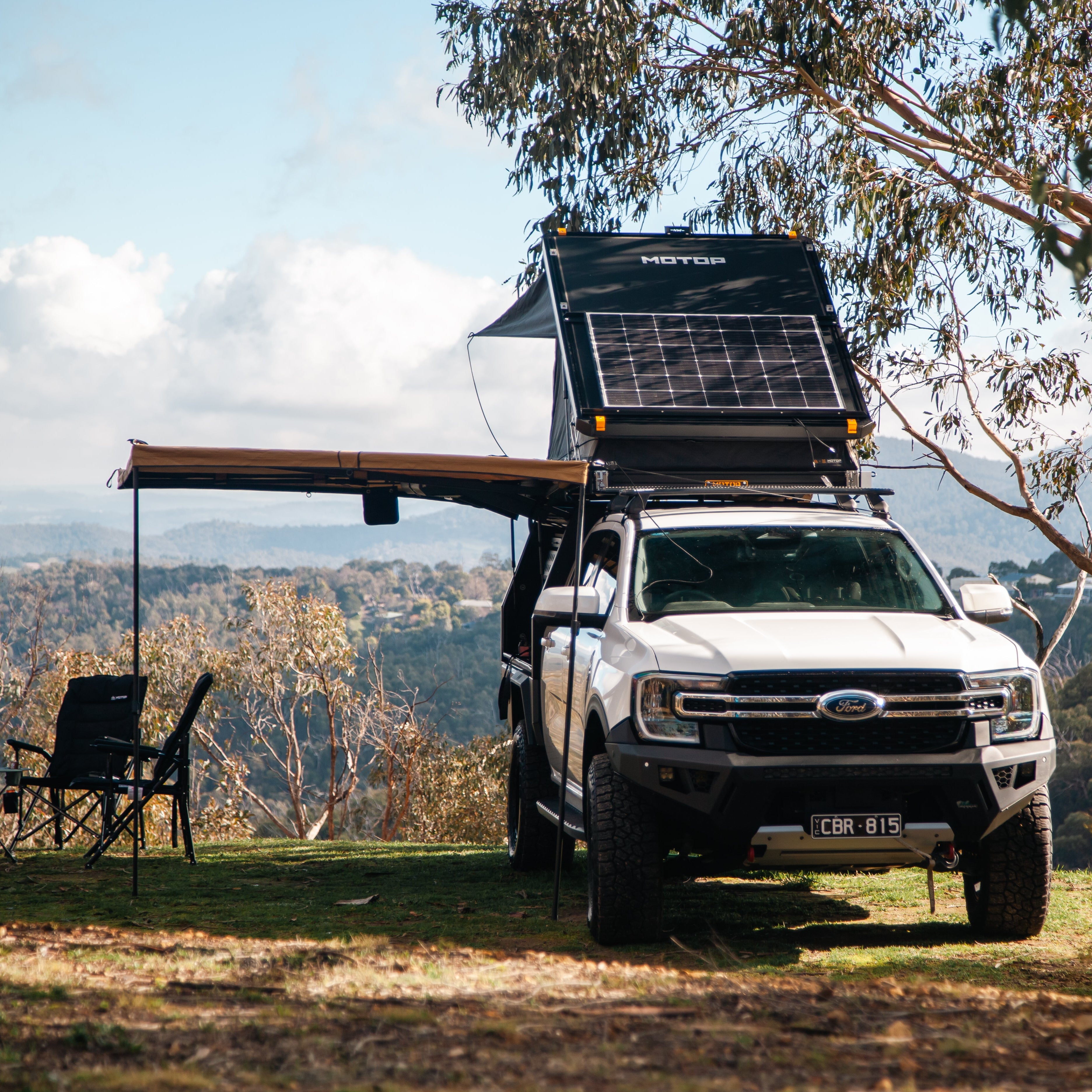 White truck with a roof rack and solar panel in a scenic outdoor setting